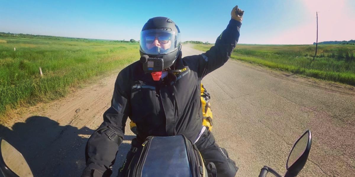 Noel Linsey of Epic Rides MB travelling down a gravel road on his motorcycle during a moto camping adventure in Manitoba.